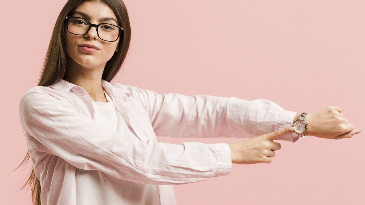 Девушка с часами на руке на розовом фоне 