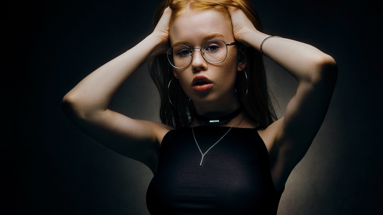 Рыжеволосая девушка в очках на черном фоне