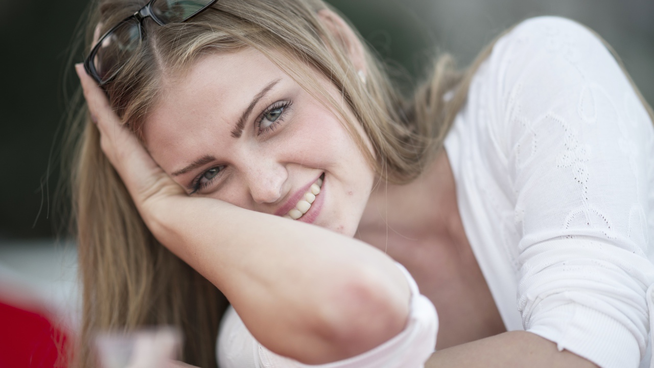 Улыбающаяся девушка блондинка с очками на голове