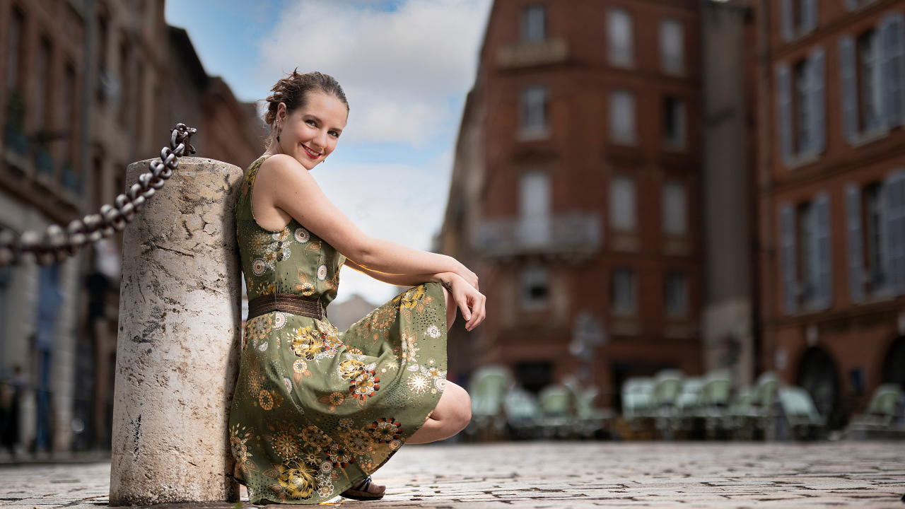 Улыбающаяся девушка в платье на улице города