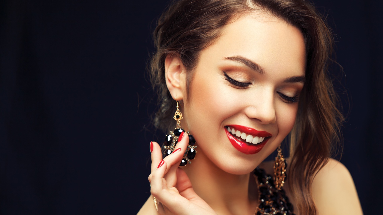 Улыбающаяся девушка носит украшения с черными камнями