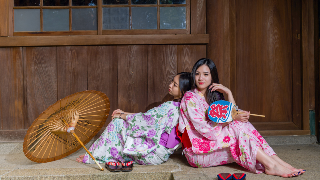 Две молодые девушки в кимоно сидят на полу