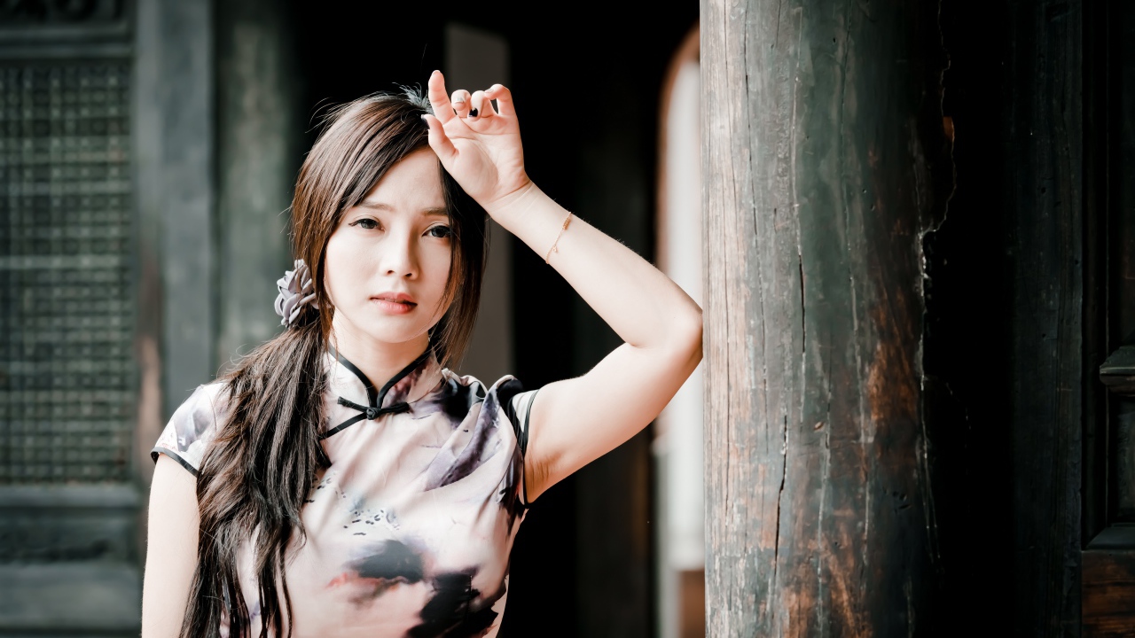 Молодая девушка азиатка стоит у столба 