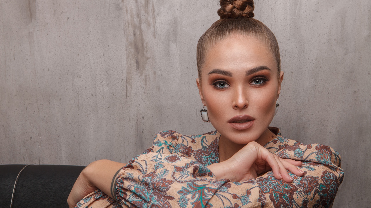 Молодая девушка с прической на голове на фоне стены