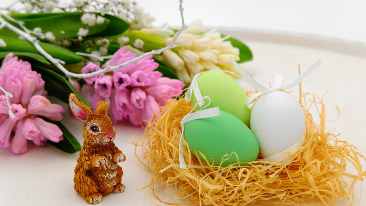 Три пасхальных яйца в гнезде на столе с цветами