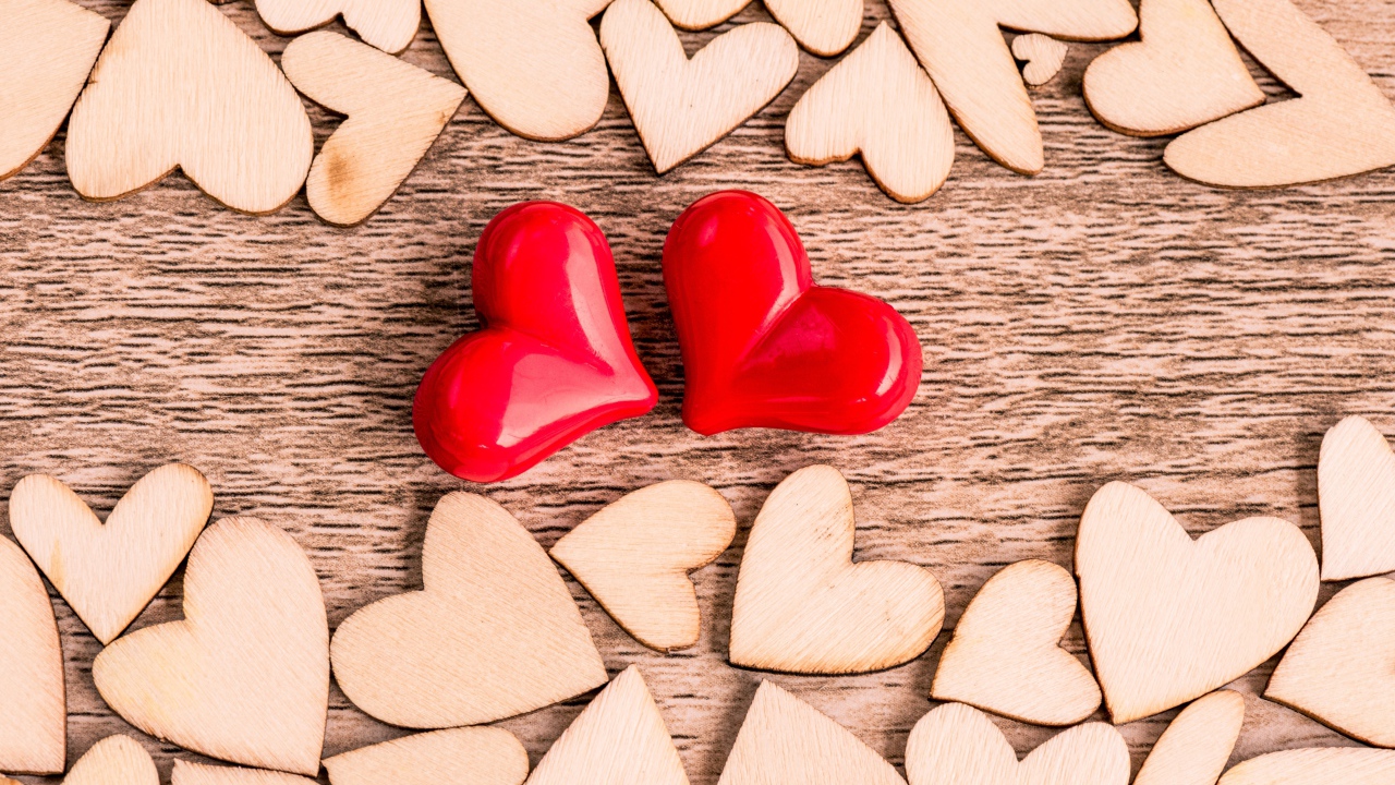 Two red hearts and wooden hearts on the table