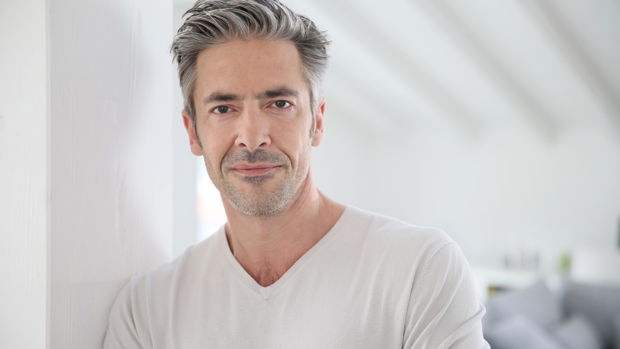 Седой стильный мужчина у стены