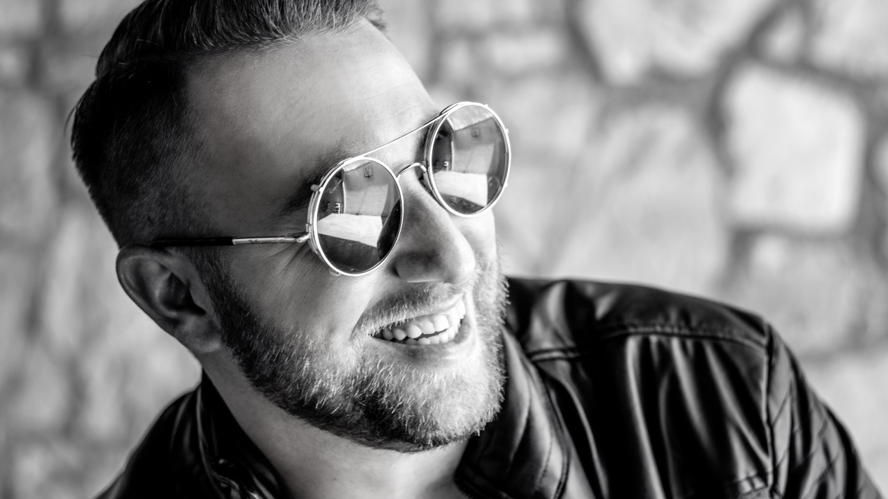 Улыбающийся брутальный мужчина в черных очках