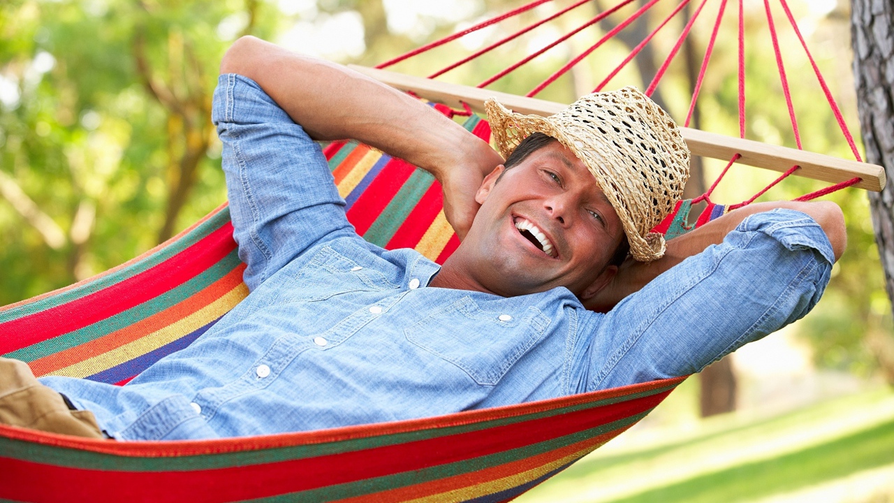 Улыбающийся мужчина спит в гамаке