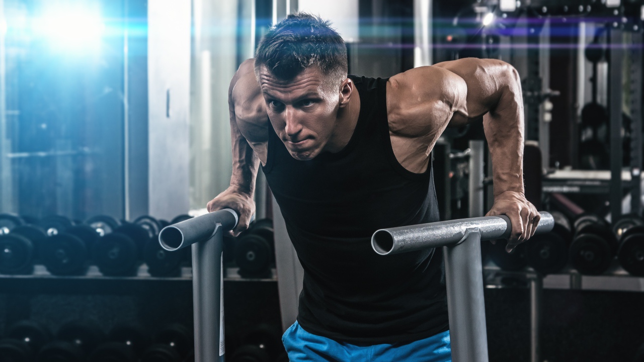 Сильный накаченный мужчина занимается в спортзале 