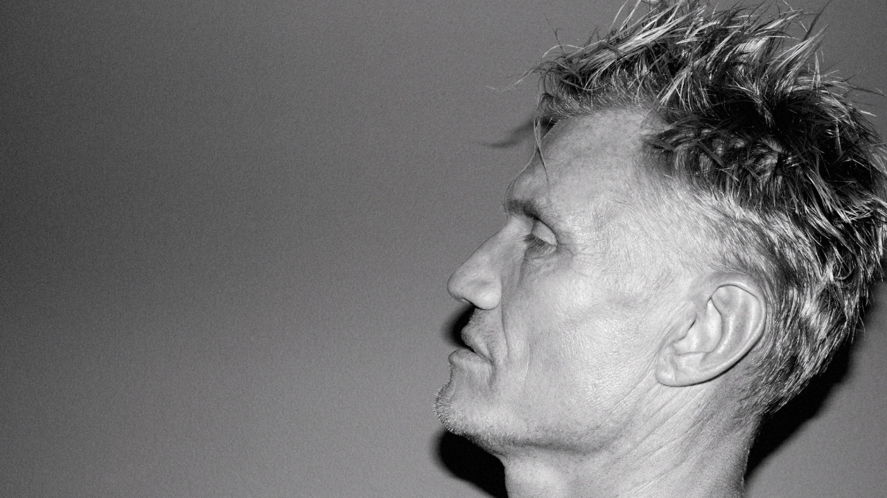 Лицо актера Дольфа Лундгрена боком на сером фоне