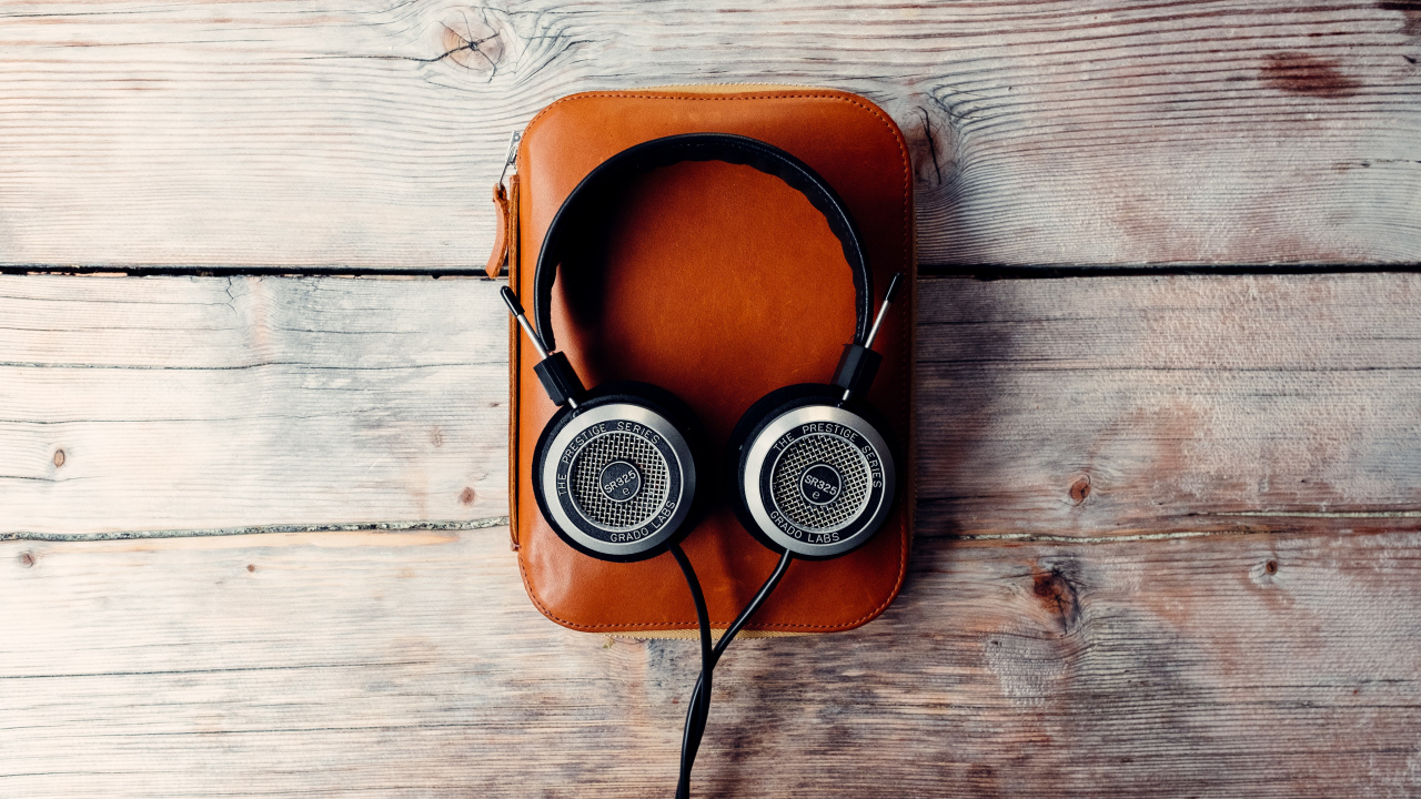 Наушники и плеер в чехле на деревянном столе