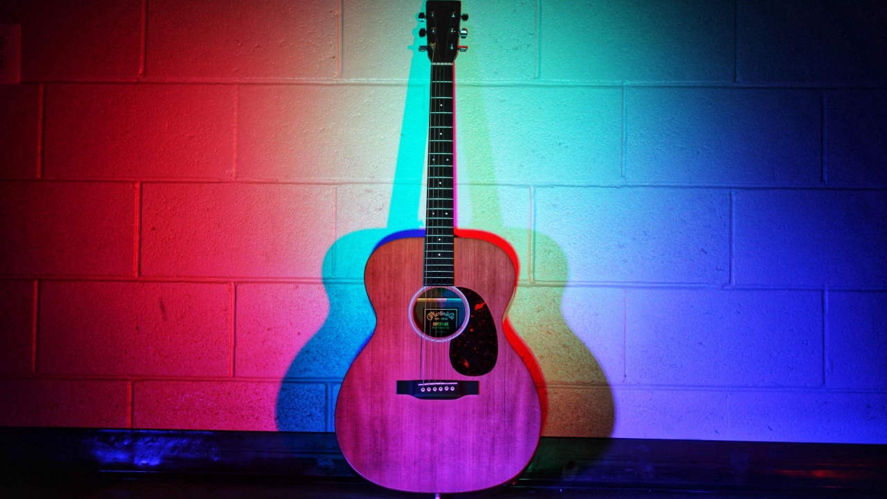 Гитара стоит у стены в разноцветном свете 