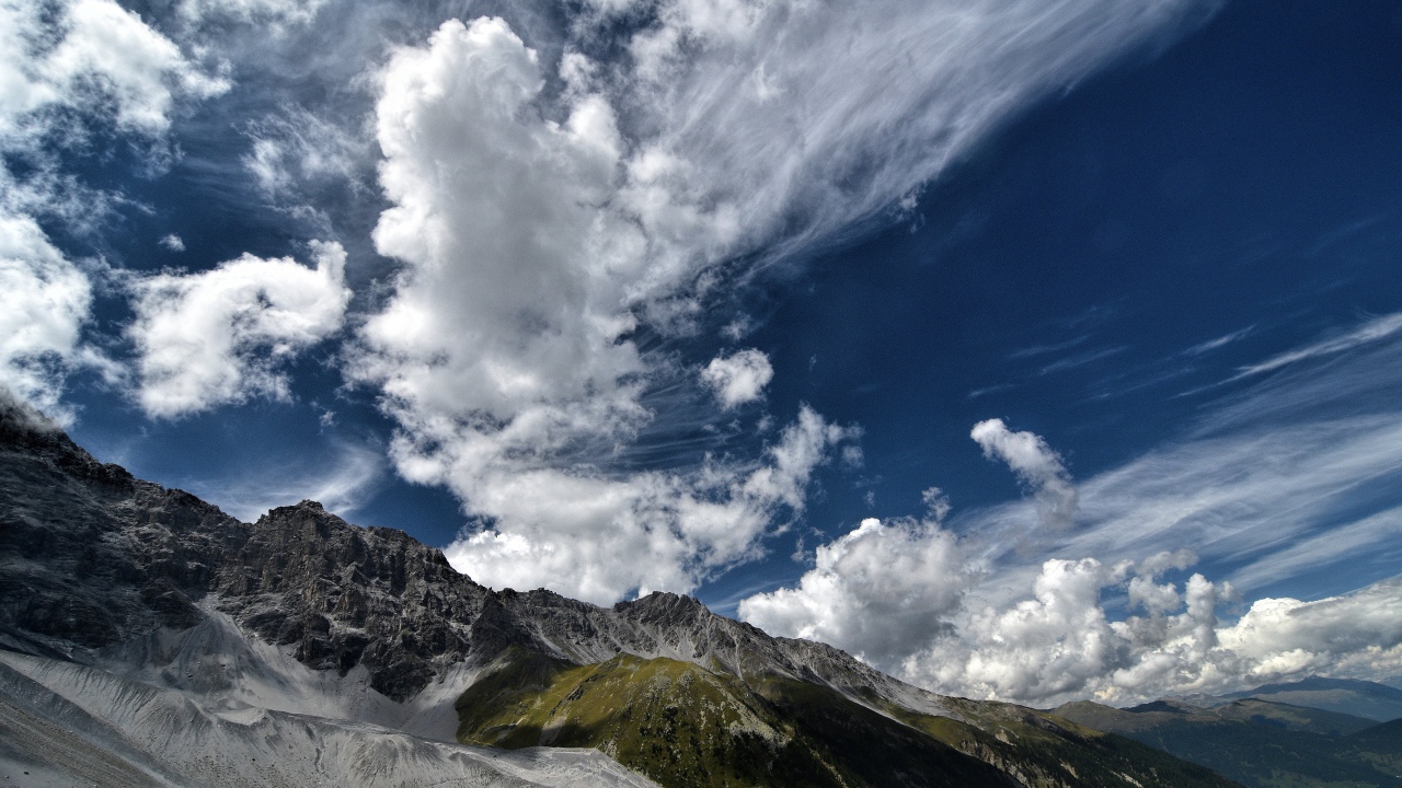 Белые густые облака в голубом небе над горами 