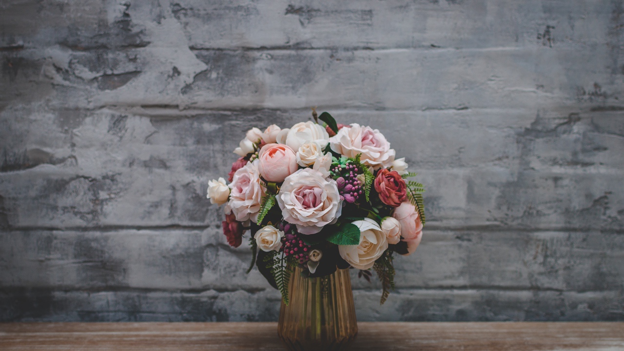 Розовый букет роз  стоит у серой стены 