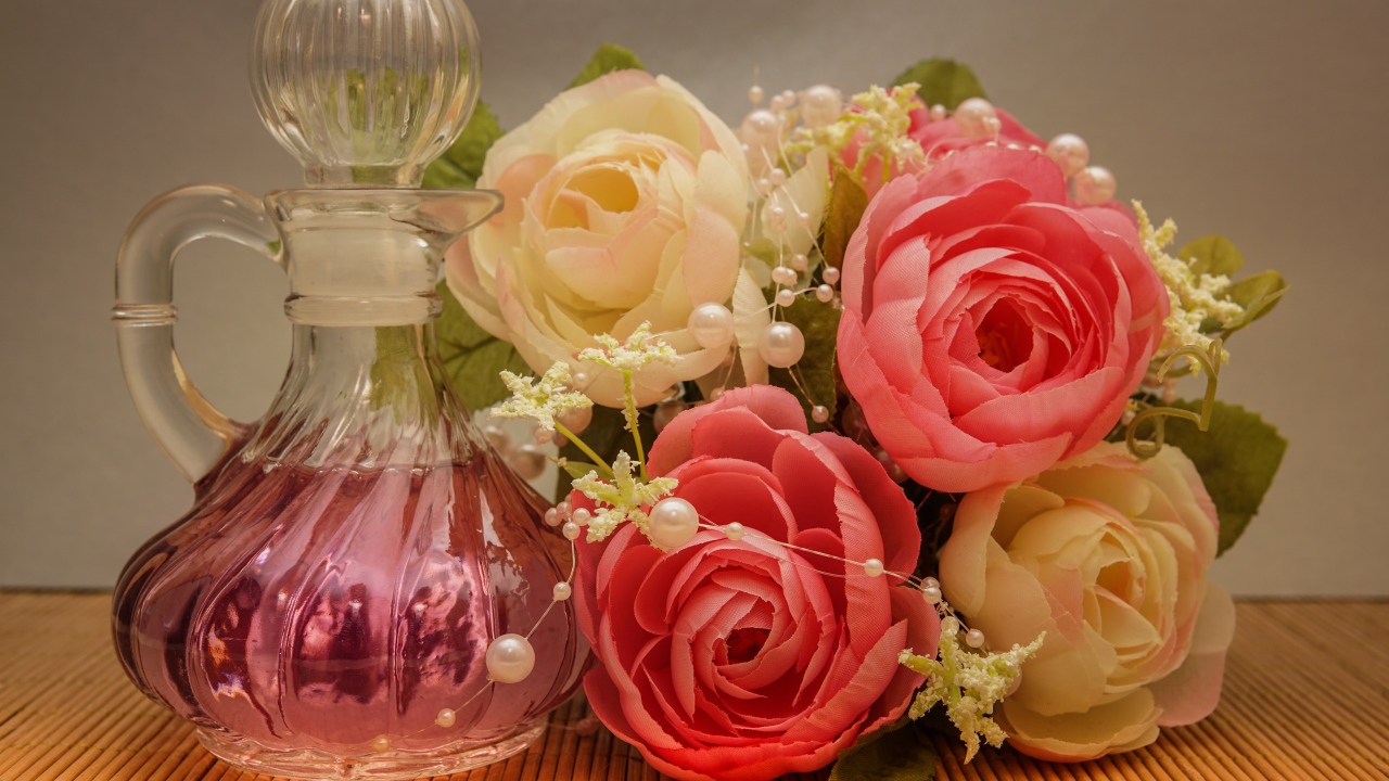 Красивый букет искусственных роз на столе с духами