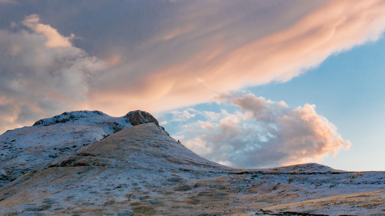 Красивые серые облака над заснеженной горой 