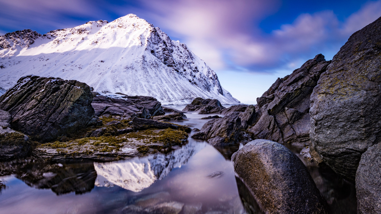 Заснеженные горы у ручья под красивым небом 