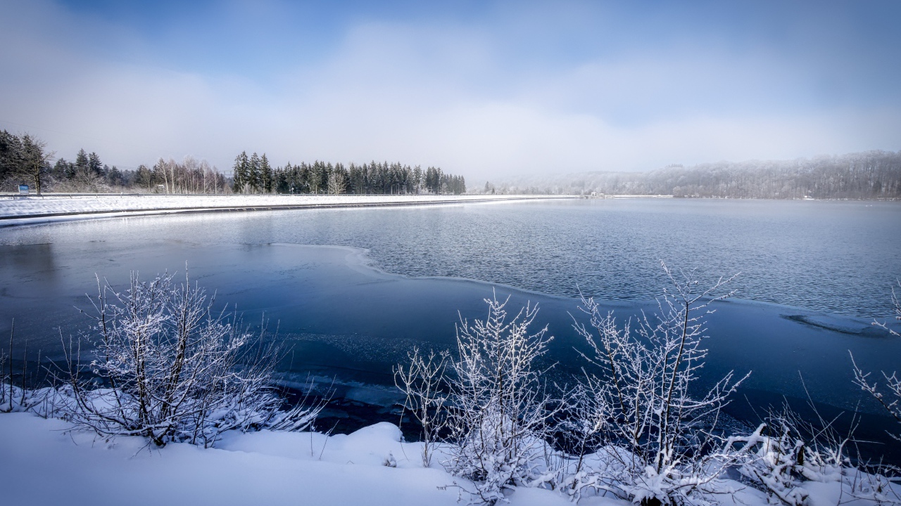 Покрытая льдом река  с заснеженными берегами зимой