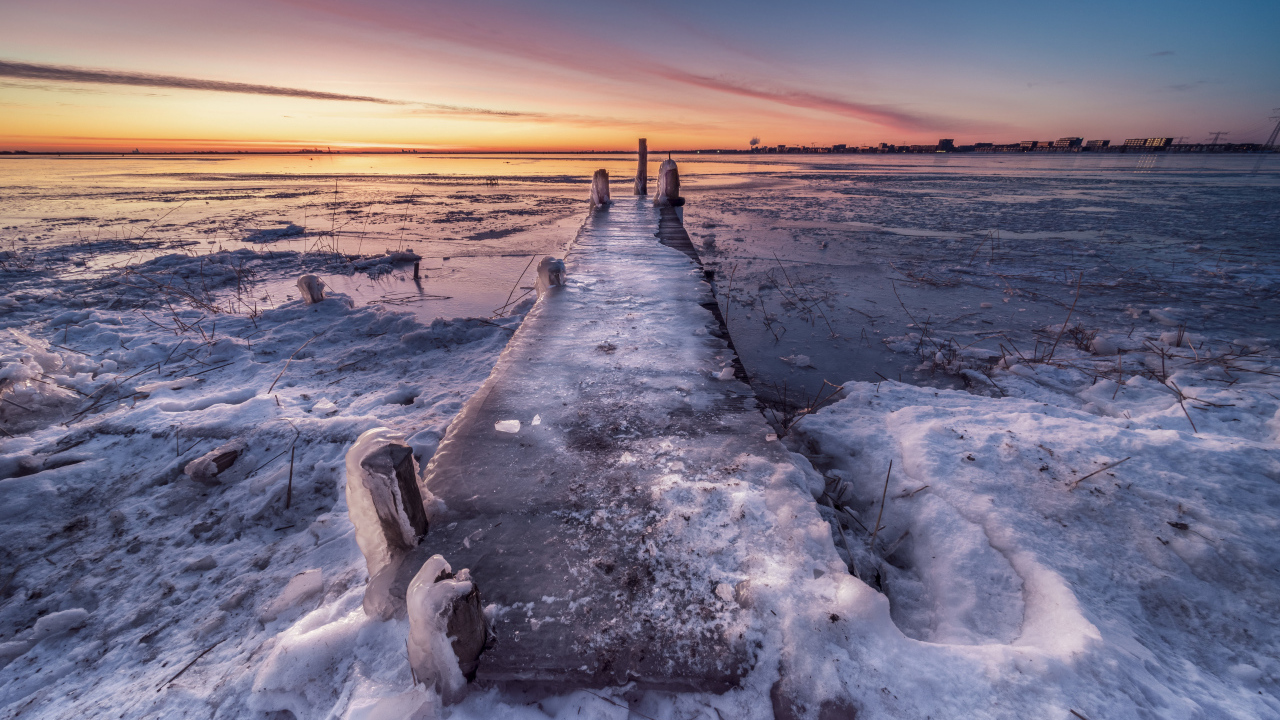 Покрытый льдом деревянный мост у озера 
