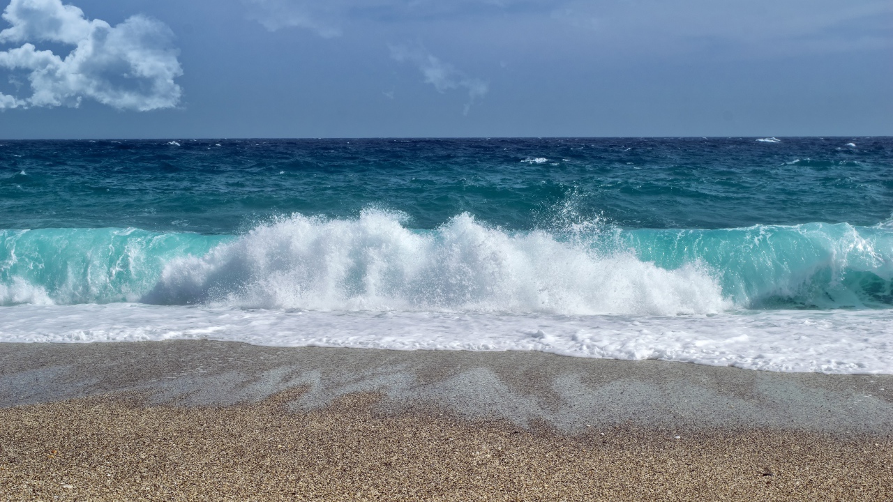 Голубые волны океана на мокром песке 