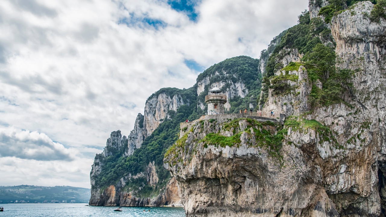 Высокие скалы у моря под белыми облаками 