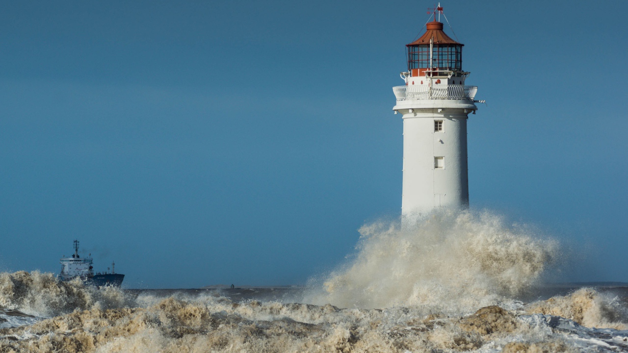 Бушующие белые волны бьются о маяк 