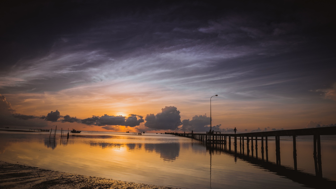 Деревянный мост на реке в лучах  солнца на закате