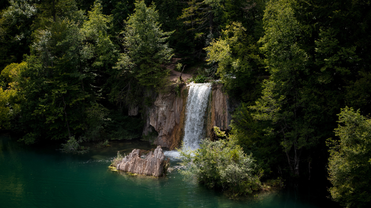 Водопад стекает со скалы в холодное озеро 