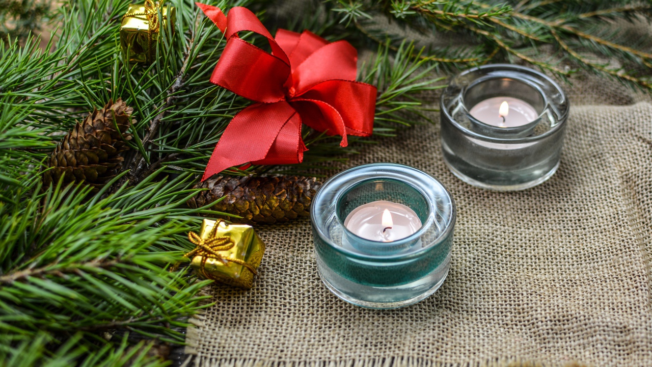 Две зажженные свечи, еловая ветка и красный бант на рождество 