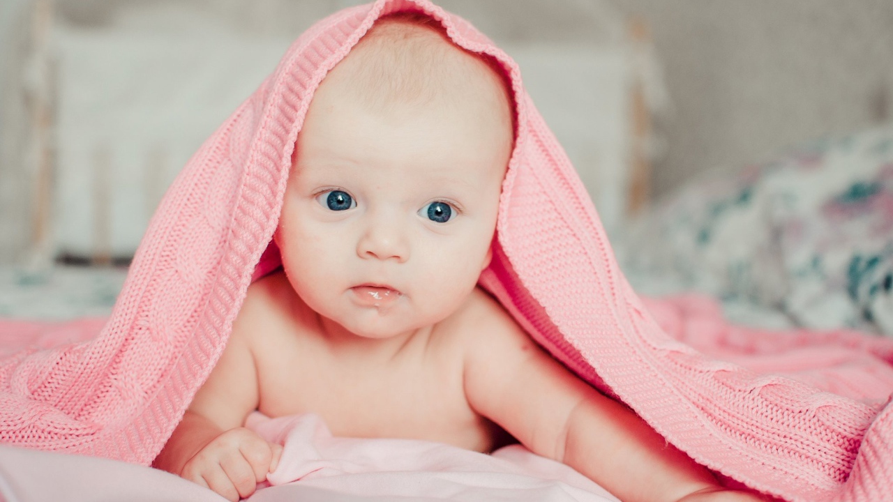 Грудной ребенок лежит под розовым пледом