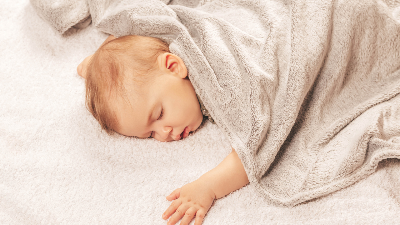 Грудной спящий ребенок под одеялом 