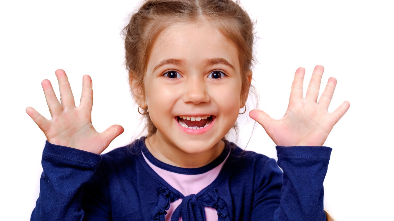 Веселая маленькая девочка с поднятыми руками