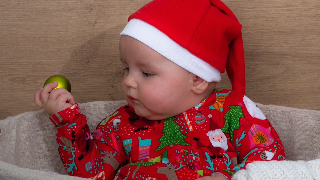 Ребенок в новогодней шапке с игрушкой в руке