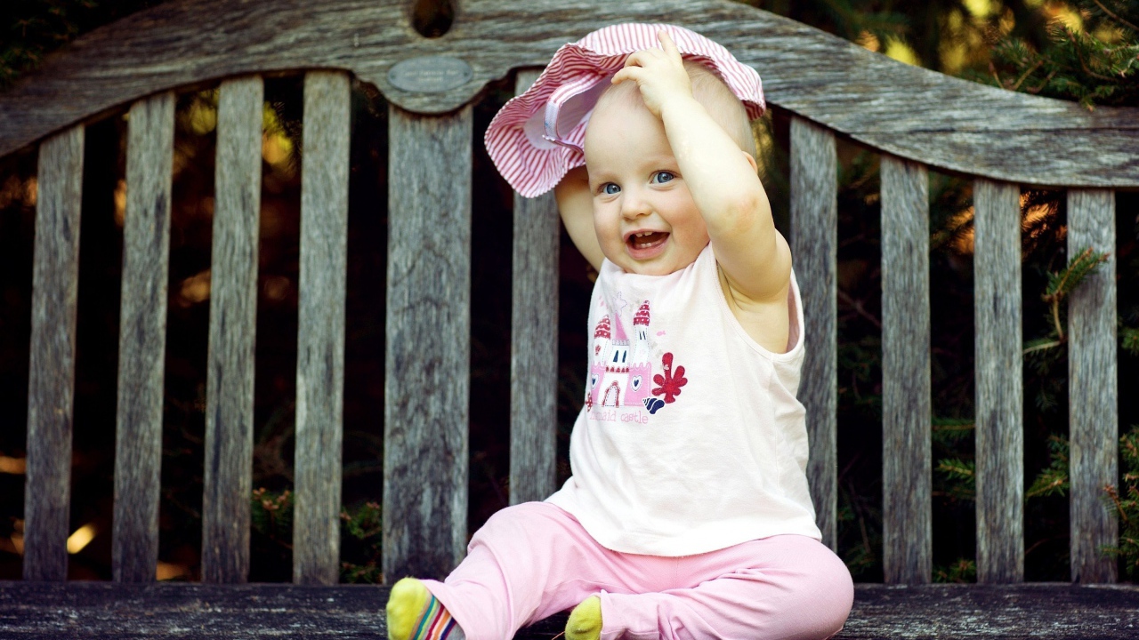 Смешной маленький ребенок сидит на лавке