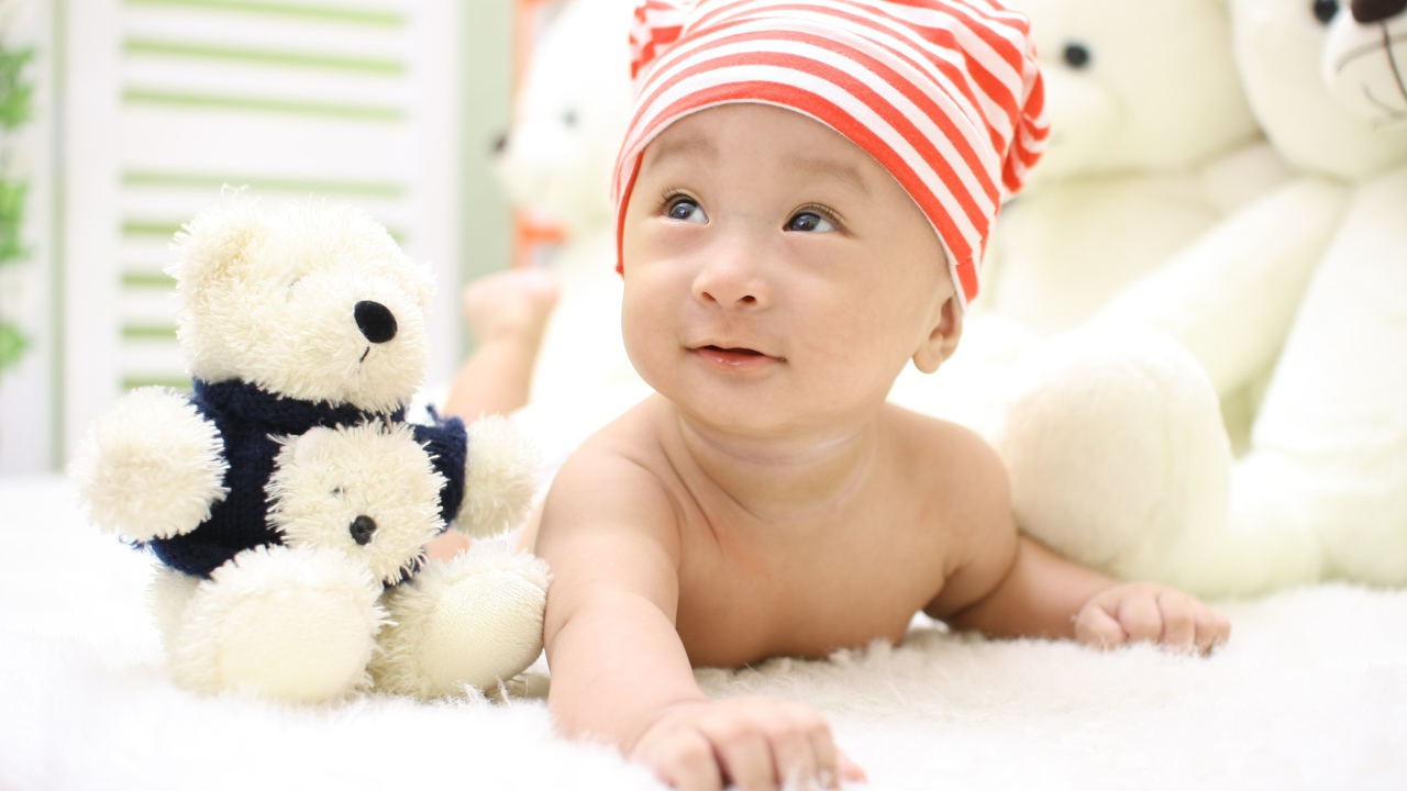 Маленький мальчик азиат на кровати с игрушкой