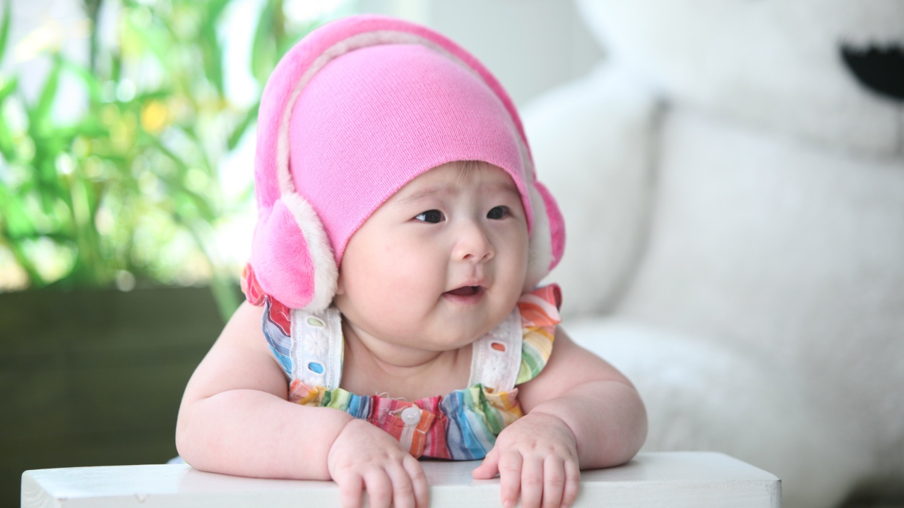 Маленький ребенок азиат в розовой шапке 