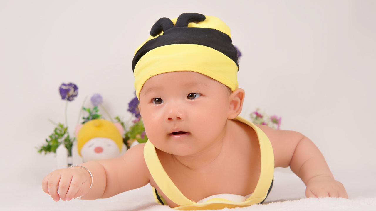 Маленький мальчик в шапке пчелы на сером фоне 