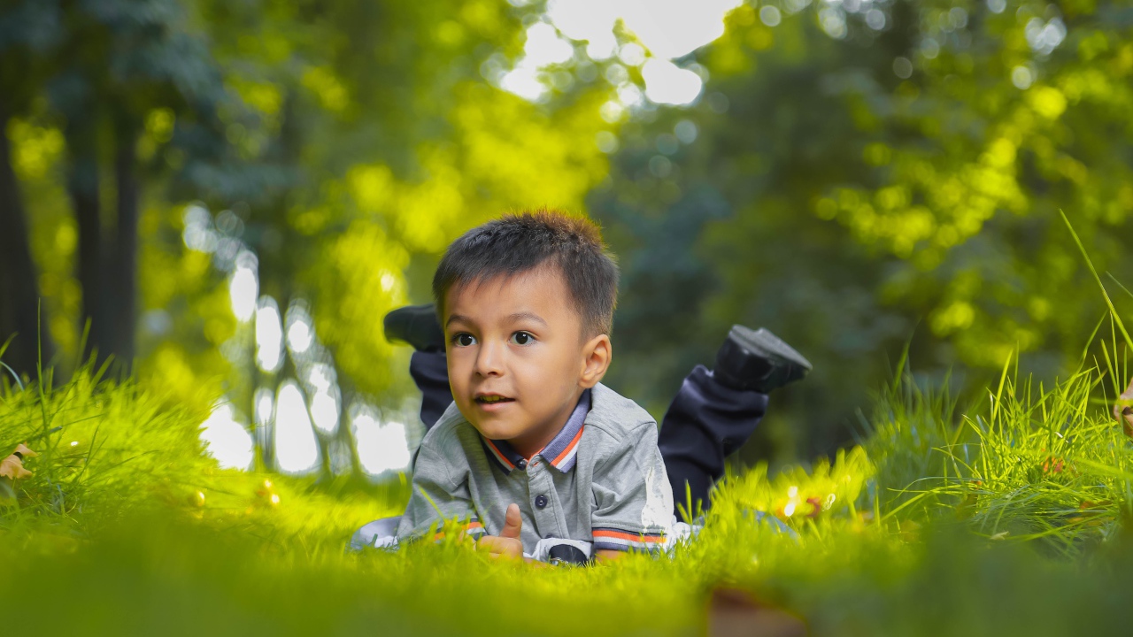Маленький мальчик лежит на зеленой траве 