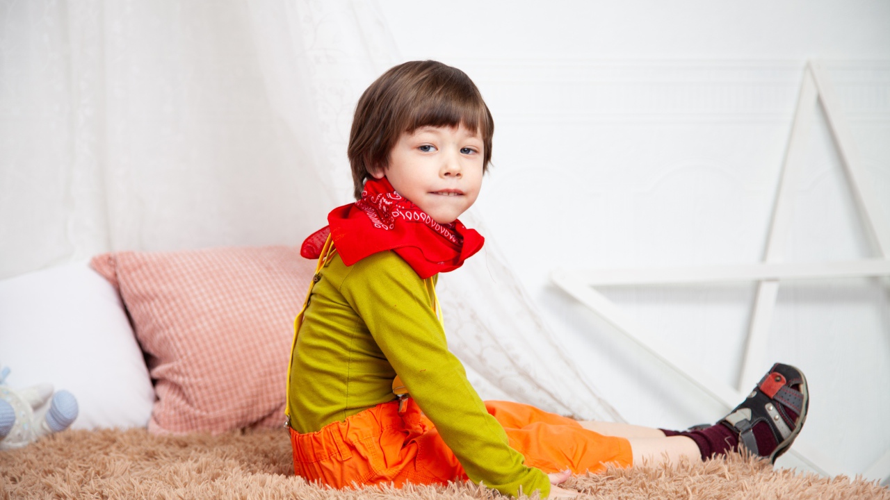 Маленький мальчик сидит на кровати