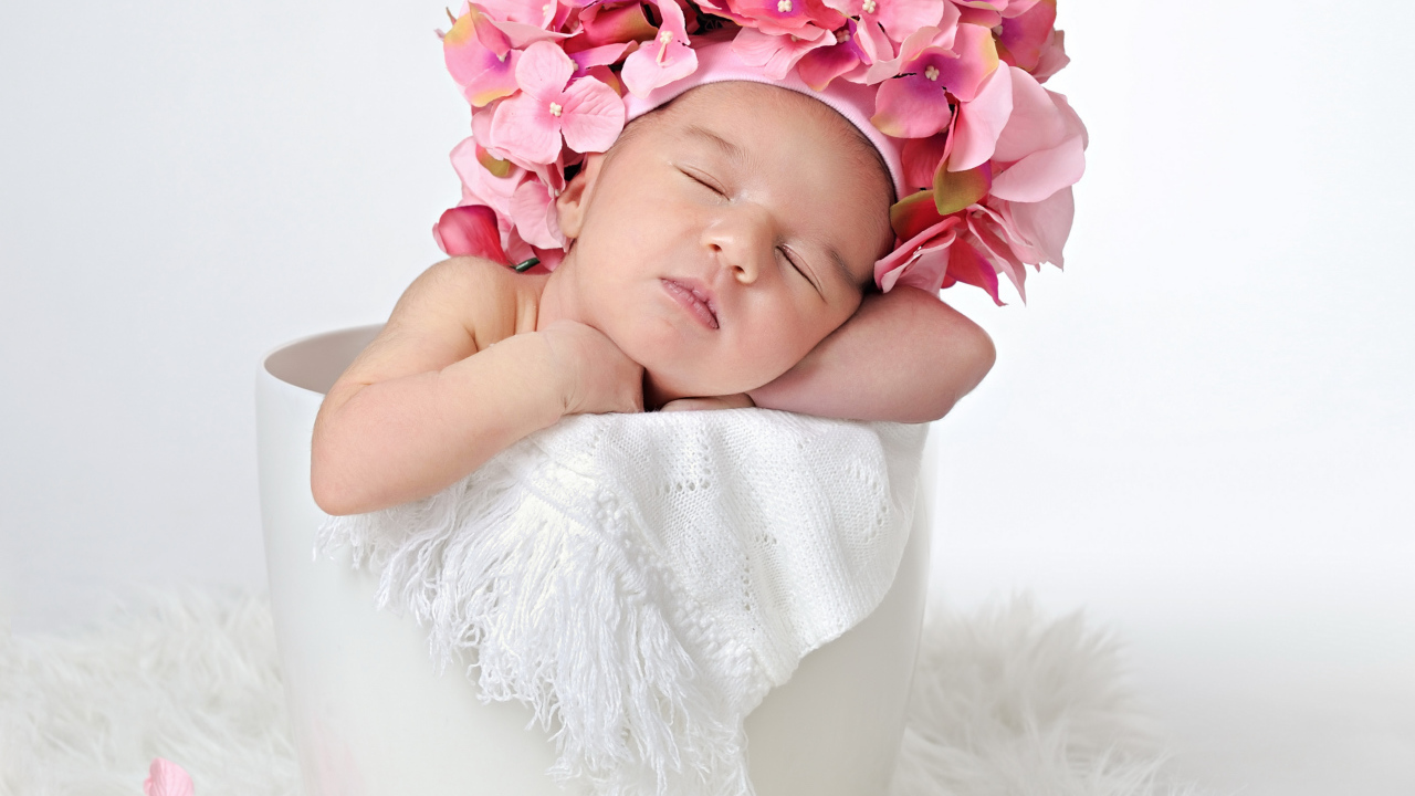 Маленький ребенок в шапке с цветами в горшке 