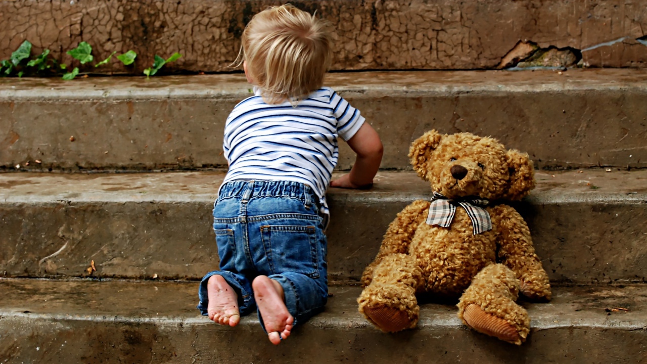 Маленький ребенок с медведем на ступеньках