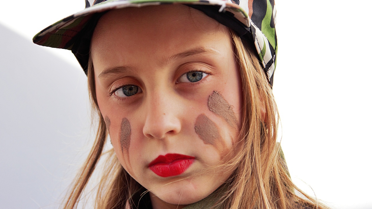 Маленькая девочка в кепке с грязью на лице