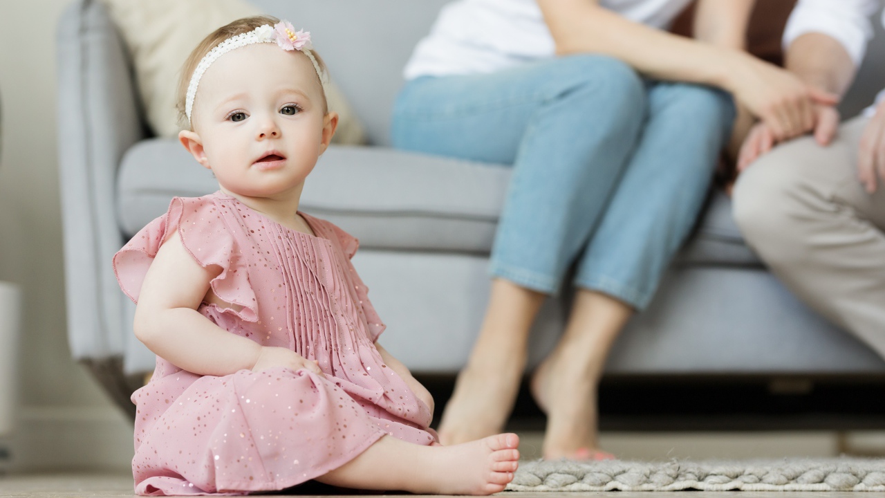 Маленькая девочка в розовом платье сидит на полу