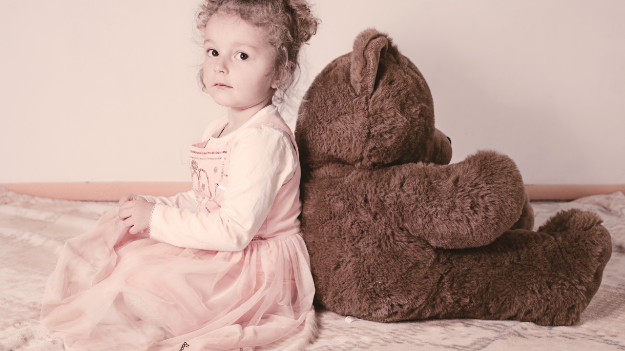 Little girl sitting with a big bear