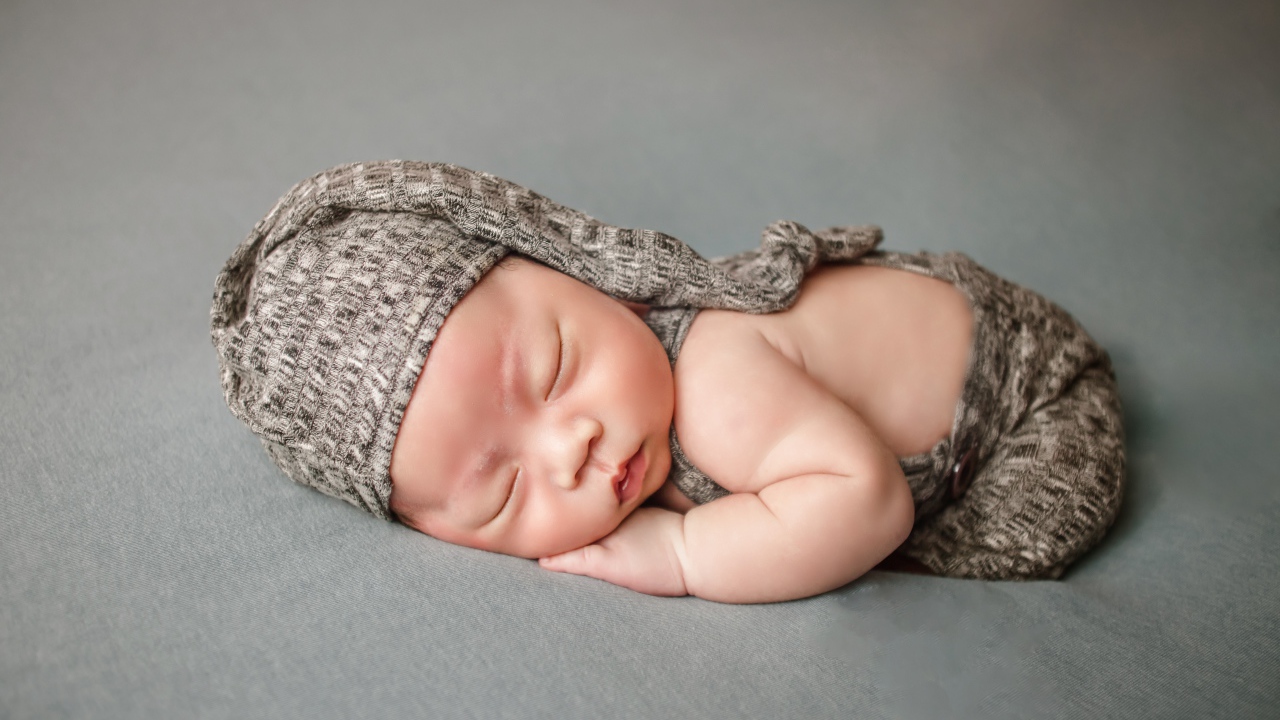 Маленький новорожденный ребенок на сером фоне