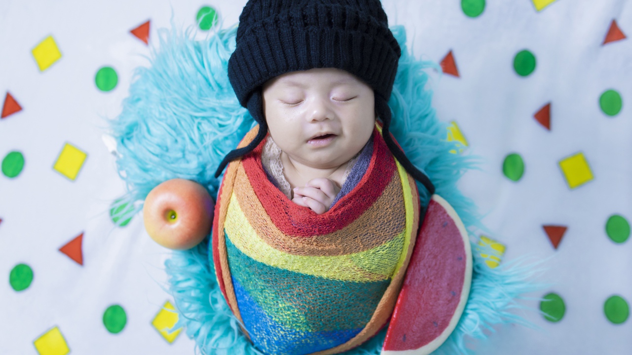 Маленький спящий ребенок в черной шапке 