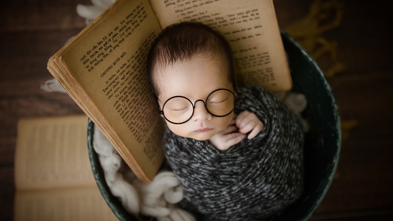 Маленький спящий ребенок в ведре с книгой 