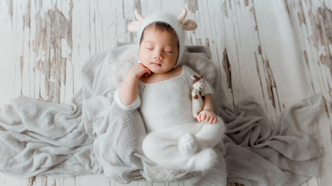 Маленький спящий грудной ребенок в белом костюме