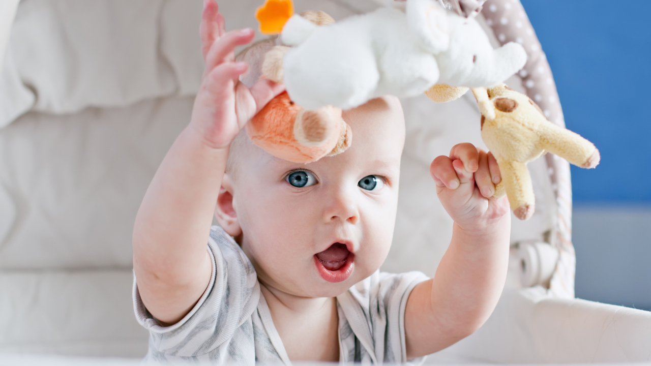 Маленький грудной ребенок в коляске с игрушками 